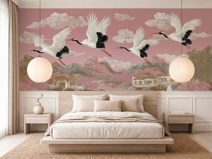 Blush pink chinoiserie crane wall mural in serene Japandi bedroom featuring flying Japanese cranes, pagodas, mountains, and cherry blossom landscape wallpaper with soft luxury Asian-inspired decor.